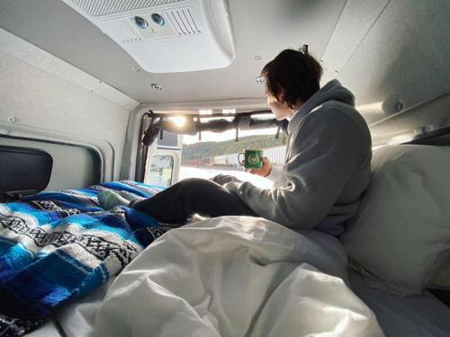 A person sitting on a bed in the back of an Antero Adventure Van